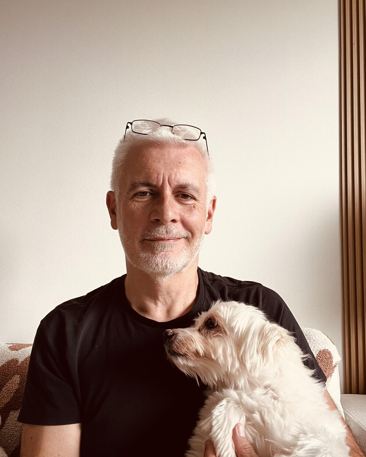 Maurizio smiling at home with his dog Fifi on his lap